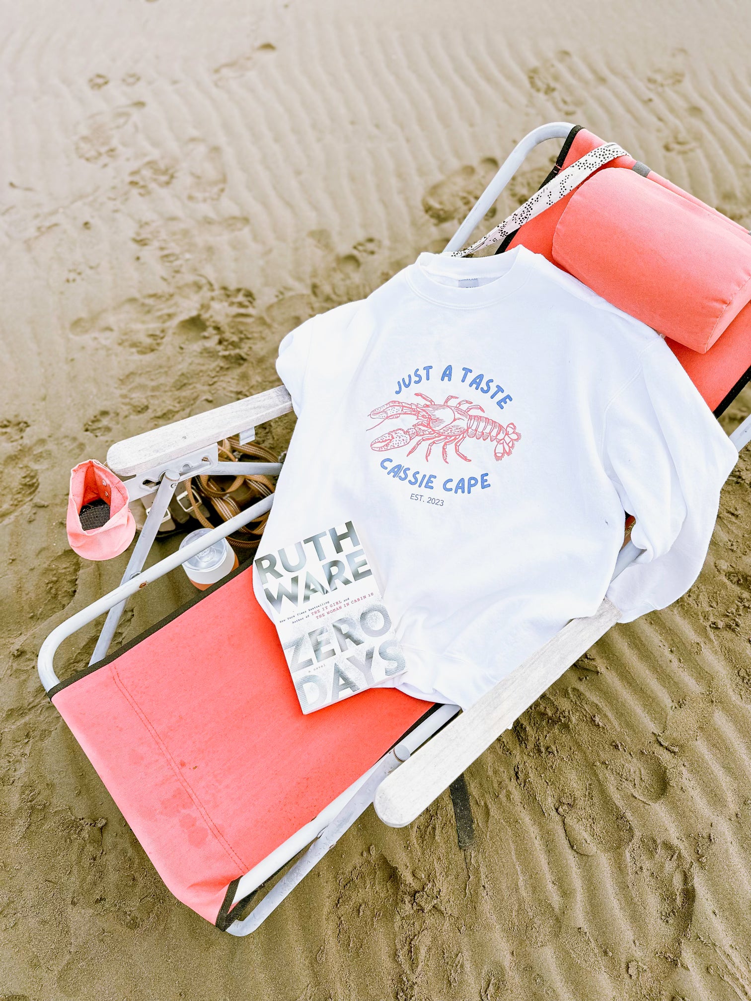 Caissie Cape sweater laid out on a beach chair with a good book, perfect for a relaxing day at the beach.